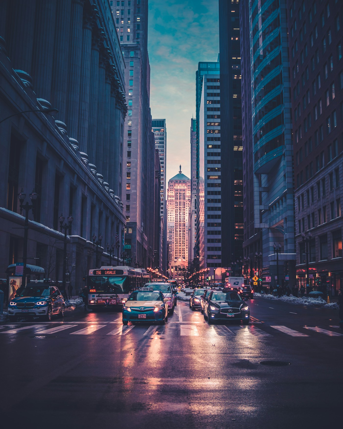 A city street framed by tall buildings at dusk