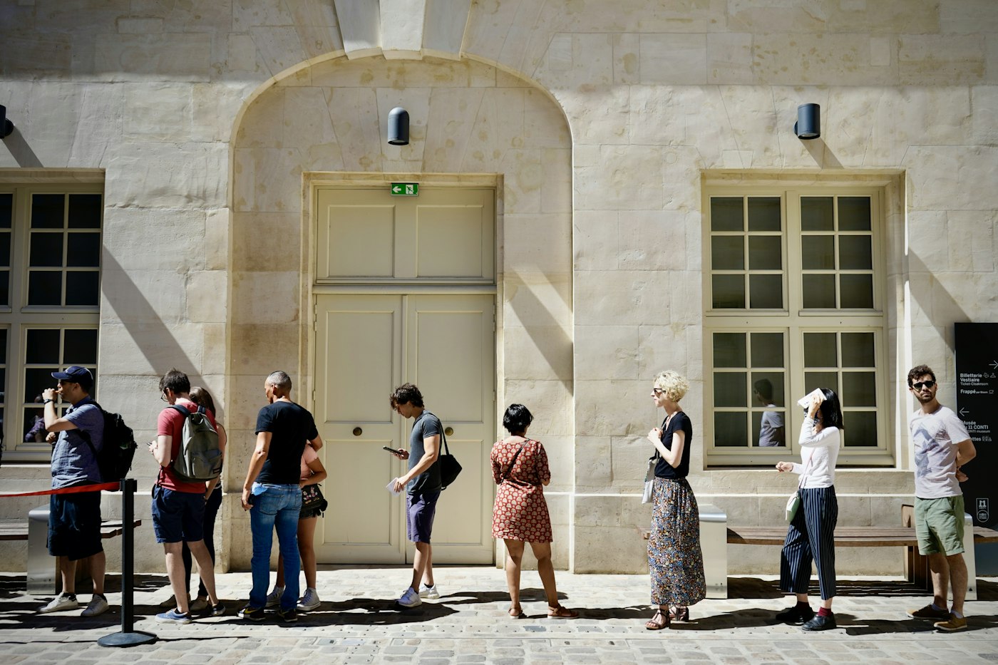People waiting in an orderly line beside a building