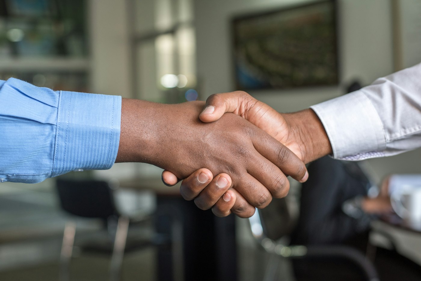Two people reaching across a table to shake hands