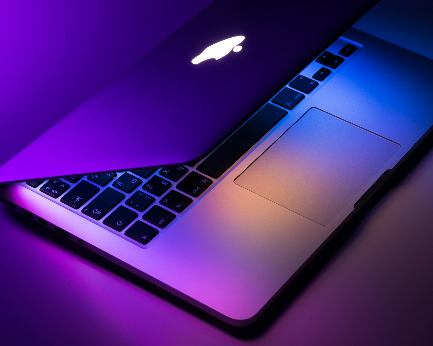 An open laptop keyboard illuminated by purple light