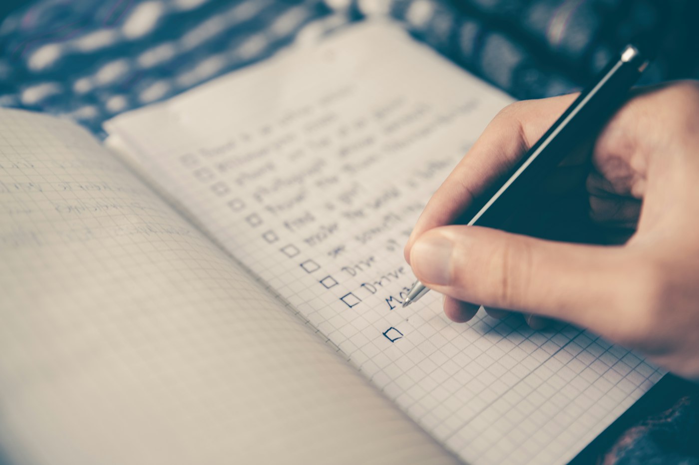 A hand writing notes on a squared notebook page