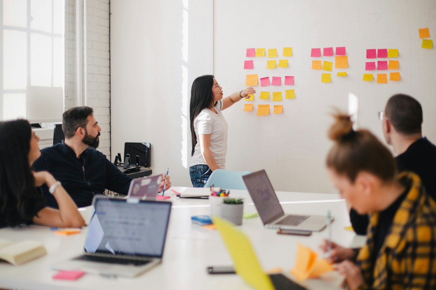 A colleague explaining a project at a wall of sticky notes