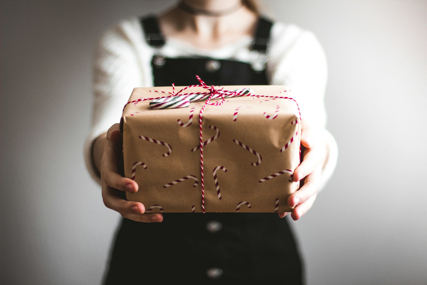 Someone offering a gift wrapped in plain paper