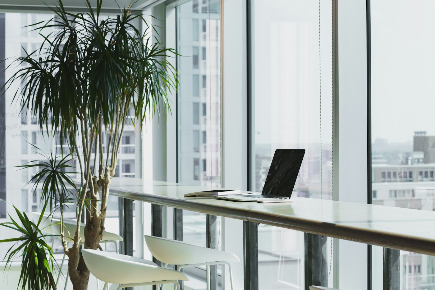 A quiet workstation with a laptop beside large windows