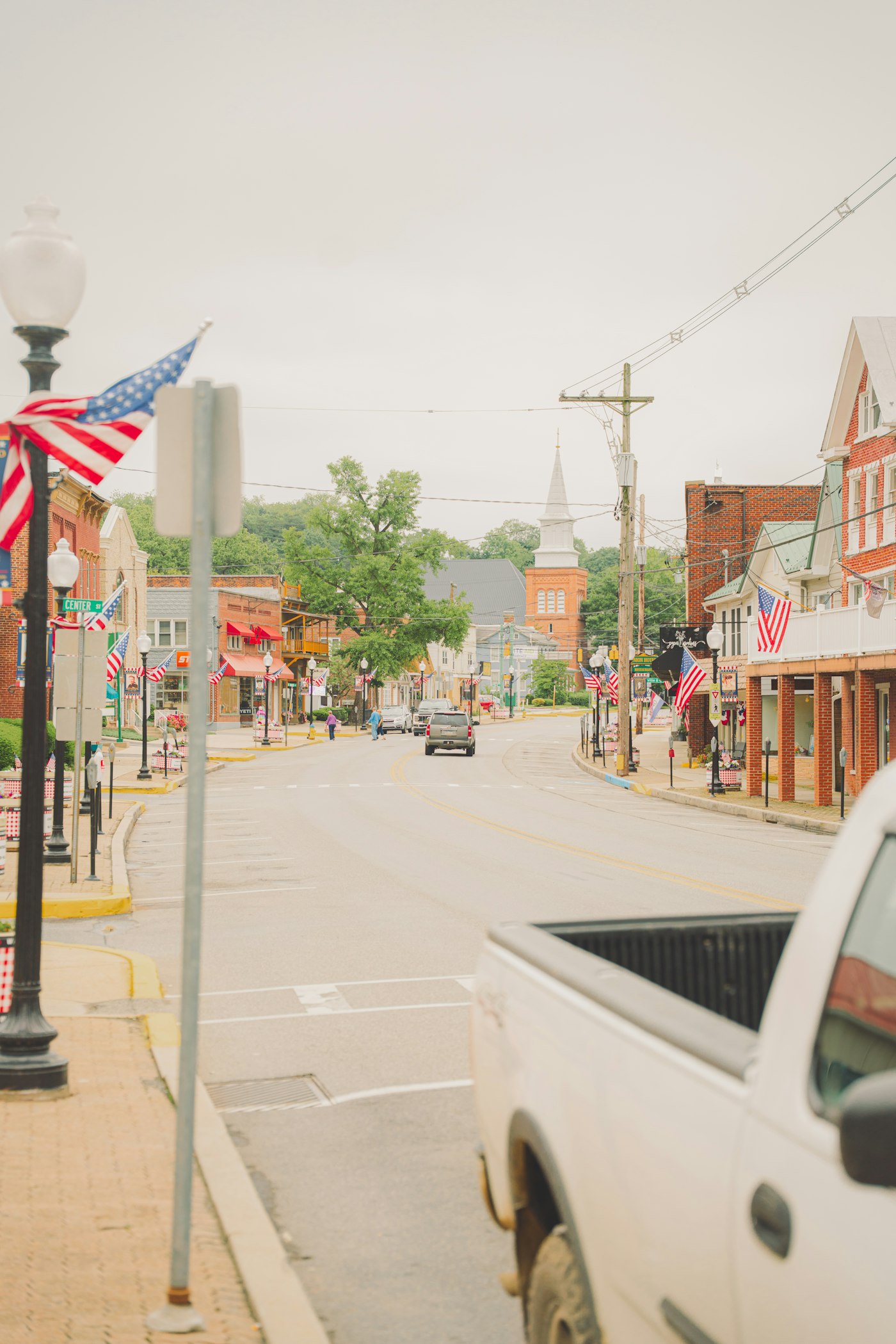 Local shops and a church steeple along a small-town street